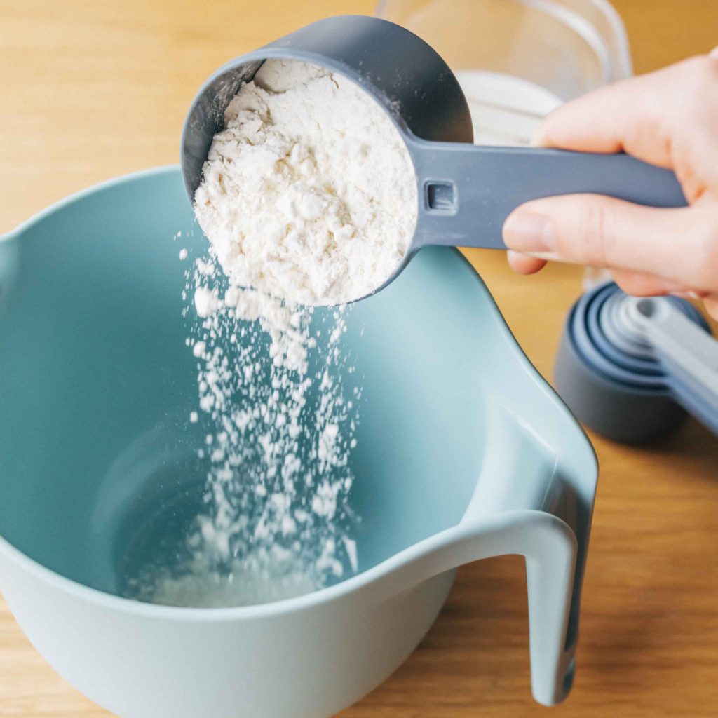 Cách làm bánh kếp bước 1: đong bột mì bằng cốc đong vào tô trộn